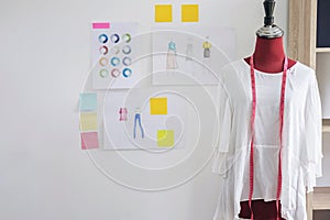 Red dummy in white clothes with measuring tape in tailors studio
