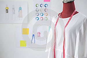 Red dummy in white clothes with measuring tape in tailors studio