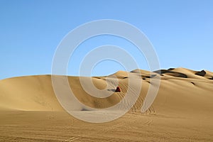 Red dune buggy running on the immense sand dune of Huacachina, Ica region, Peru