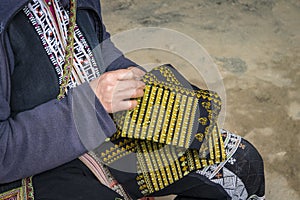 Red dzao ethnic minority woman sewing in Sa Pa, Lao Cai province, Vietnam. an elderly woman sews on street. Make beautiful