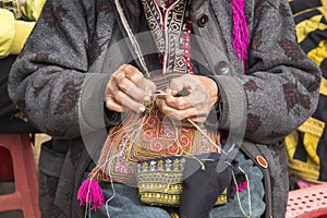 Red dzao ethnic minority woman sewing in Sa Pa, Lao Cai province, Vietnam. an elderly woman sews on street. Make beautiful