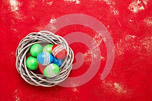 Red Easter background. Colorful Easter eggs in wreath on red background. Top view, copy space