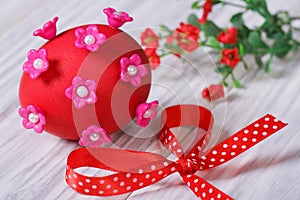 Red easter egg decorated with pink flowers with bow
