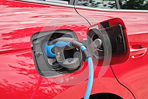 Red electric car charging - close up of charger