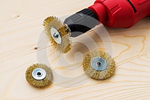 Red electric drill and three round metal wire brushes for cleaning of metal and wood and remove rust over rough wooden surface.