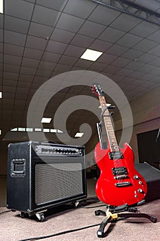 Red electric guitar and amplifier are on the stage