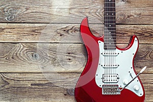 Red electric guitar on grunge wooden planks background. Place for text.