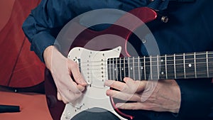 Man plays the bottom string of an electric guitar photo