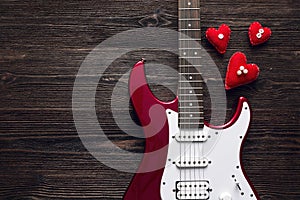 Red electric guitar with hearts on a dark wooden background. Spa