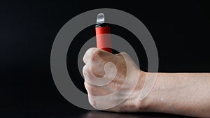 Red electronic cigarette clutched in a woman's hand on a black background. Copy space. Photo