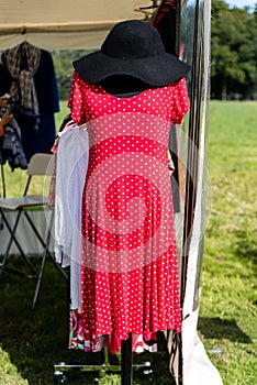 Red elegant fashion ladies red dress with short sleeves with a small white dots design and black felt hat presented on a mannequin