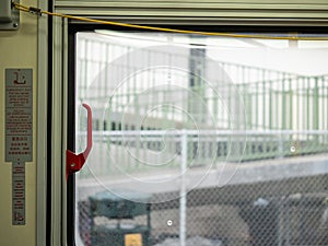 Red emergency exit handle on window on moving public transportation bus