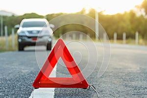 Red emergency stop sign and broken silver car on the road