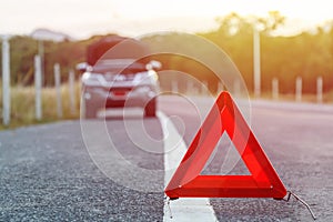 Red emergency stop sign and broken silver car on the road