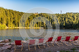 Red, empty deckchairs at Mummelsee Lake with view of the Hornisgrinde in the Black Forest