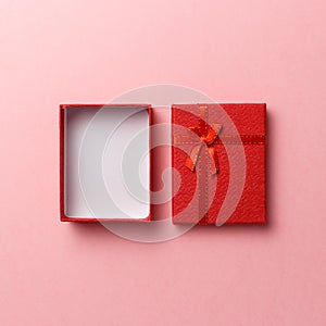 Red empty gift box with red ribbon on pink background. Top view. Flat lay. Copy space. Colorful background. Minimal christmas new