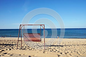 Red Empty Swing chain on Nhat Le beach Dong Hoi city Vietnam. Childen playing on beach