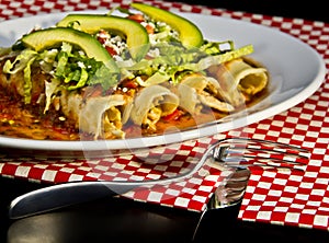 Red Enchilada with avocado slices and crumbled cheese