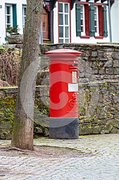 Red english mailbox in front of a stone wall in Bad Muenstereifel