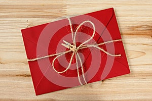 Red envelope tied with jute twine and clothespin on a wooden background