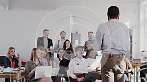 RED EPIC Group of multiethnic employees sit and listen to male African business coach at office conference slow motion.