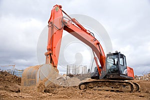 Red excavator during earthworks at construction site. Backhoe digging the ground for the foundation and for laying sewer pipes