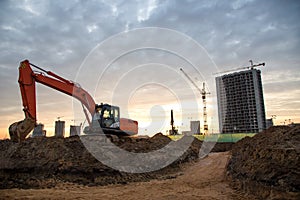 Red excavator during groundwork on construction site. Hydraulic backhoe on earthworks.