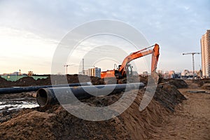 Red excavator during groundwork on construction site. Hydraulic backhoe on earthworks.