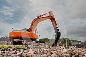 Red excavator with rock or stone grab attached to the arm. Heavy machinery equipment on a construction site