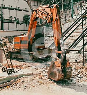 A red excavator works at a construction site
