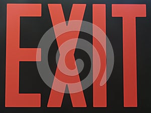 Red exit sign illuminated in the darkness