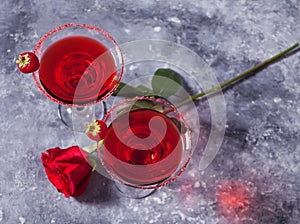 Red exotic alcoholic cocktail in clear glasses and red rose for romantic dinner