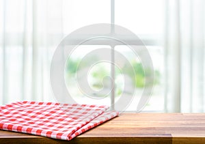 Red fabric,cloth on wood table top on blur window in morning background.For montage product display or design key visual