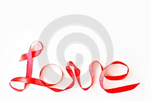 Red fabric ribbon forms the word love on a white background. Top view, isolated. Valentine`s Day Concept, February 14th