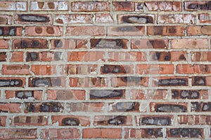 Red faded burned old bricks background with flaws and splits