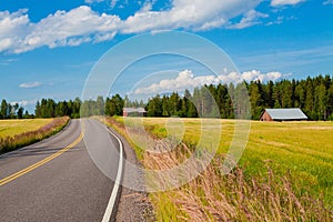 Red farm with the road, blue sky and green field