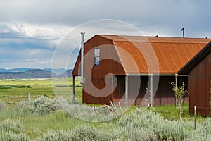 Red farm shed in a big grassland farm field