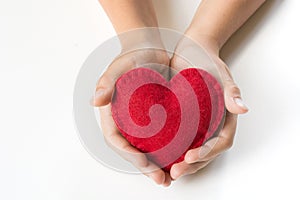 Red felt heart in childs hands on white. Copy space.