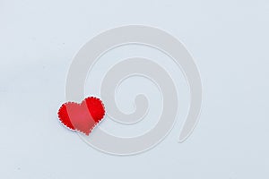 Red felt heart with white stitches. A symbol of love handmade sewn with thread around the edge on a white background