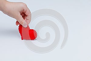 Red felt heart with white stitches. A symbol of love handmade sewn with thread around the edge on a white background