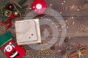 Red felt stocking with the image of Santa Claus, fir branches, cones and Christmas tree decorations, a candle, gold beads on a