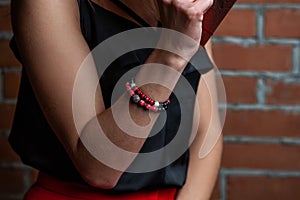 Red female bracelet made of natural and precious stones, brick wall background