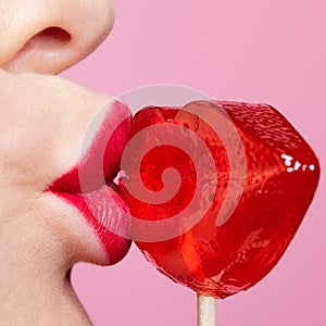 Red female lips shape lollipop. Close-up of woman lips kissing candy. Sweet tooth concept