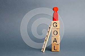 The red figure of a man stands on a tower of cubes with the word goal. Leadership skills. The concept of achieving the goal