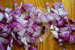 Red finely chopped juicy onion lezhin on a brown wooden kitchen board.