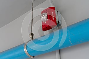 Red Fire alarm lighting above PVC pipe against white background