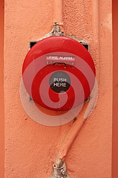 Red fire alarm on orange wall