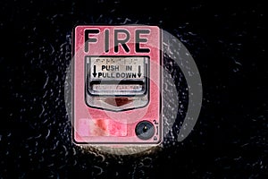 Red fire alarm switch at cement wall