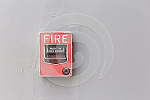 Red fire alarm switch on exterior cement wall of commercial building, safety concept.