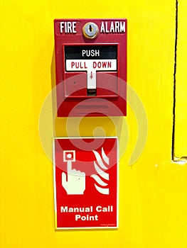 Red fire alarm switch on a vibrant yellow wall with instructions